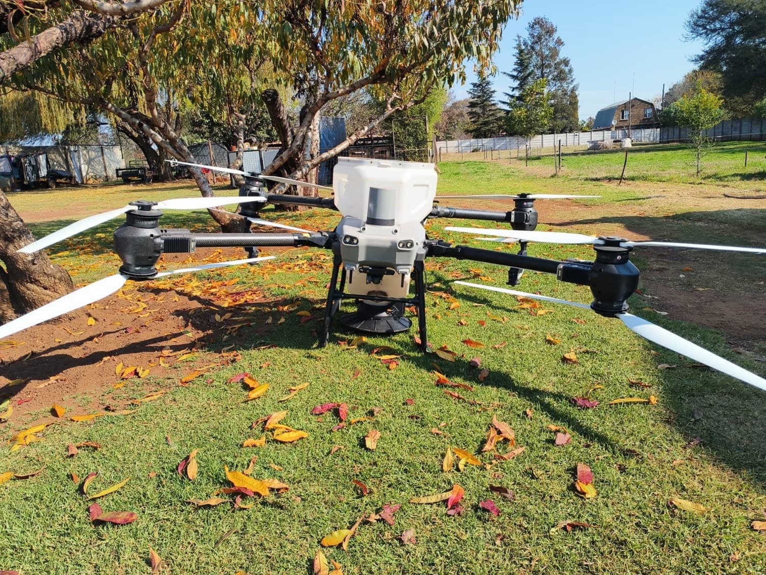 An agricultural spray drone on grass, arms unfolded