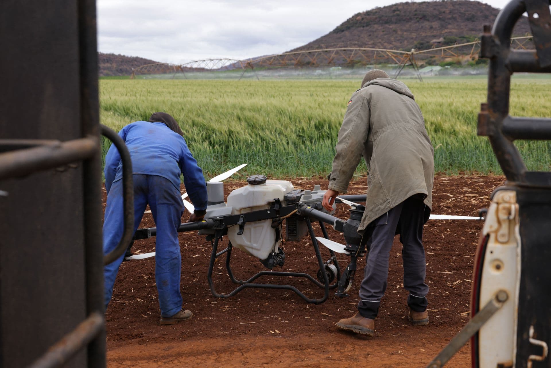 Two farmers preparing an agricultural drone in a field